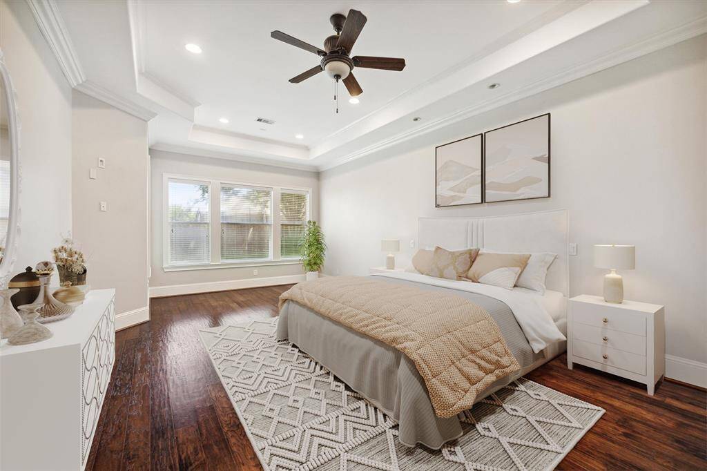 Step into the luxurious primary bedroom, where you’ll be immediately drawn to the custom crown molding, soaring vaulted ceilings, and rich wood flooring that exudes warmth and sophistication. This spacious retreat offers both style and comfort, creating the perfect environment for relaxation and rest. The thoughtful design and attention to detail make this room a true sanctuary. (Digitally Staged)