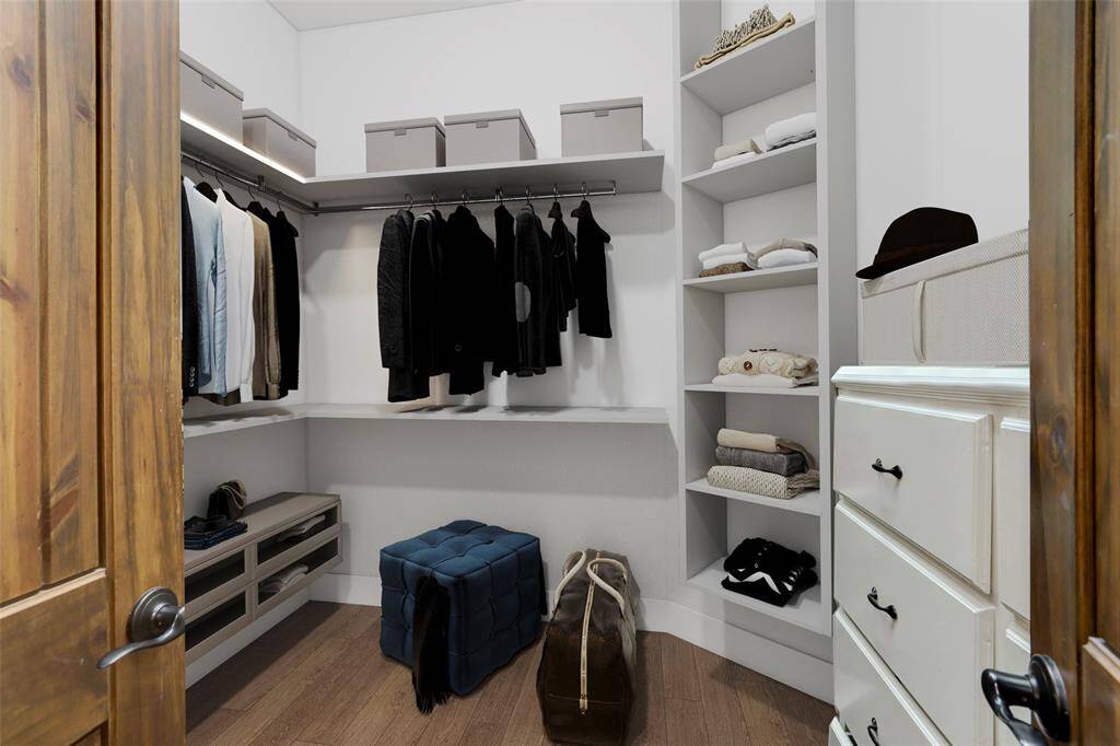 This spacious walk-in closet offers an ideal combination of style and functionality, featuring built-in shelving and hanging rods to neatly organize clothing and accessories. With thoughtful design details throughout, this closet is perfect for those seeking both convenience and luxury in their everyday routine. (Digitally Staged)