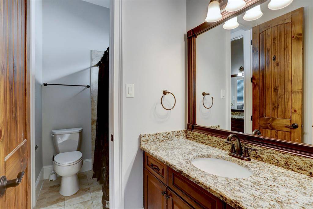 This secondary bathroom seamlessly combines style and function, starting with a warm wood door that complements the rich cabinetry and granite vanity. Perfect for both daily routines and guest accommodations, this bathroom offers a harmonious blend of comfort and sophistication.