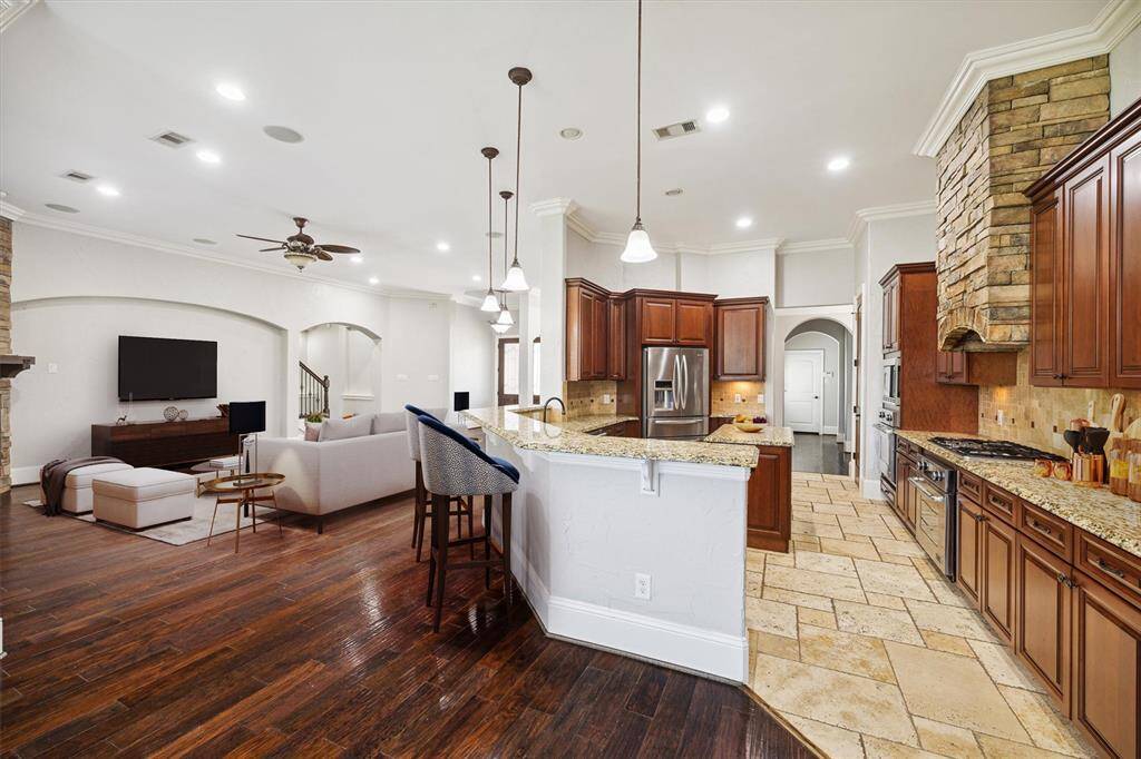 From the vantage point of the breakfast area, you’ll appreciate the expansive open floor plan that seamlessly connects the living room, dining area, and kitchen, creating a perfect flow for both everyday living and entertaining. The thoughtfully designed layout enhances the sense of space and connectivity, while the kitchen stands out with its beautiful stone flooring, adding a touch of elegance and durability. (Digitally Staged)