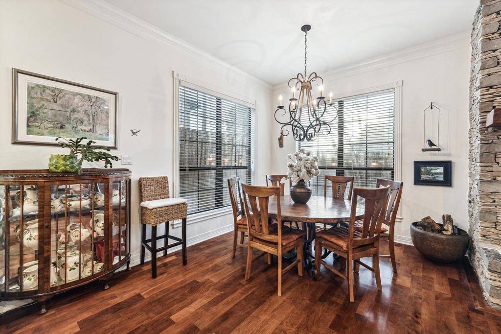 This dining room features rich hardwood floors, large windows, and an elegant chandelier.