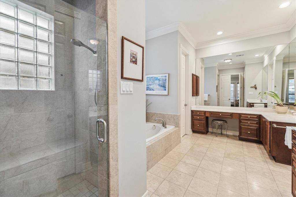 This en-suite feature a large walk-in shower with dual shower heads, a separate soaking tub and marble flooring. It offers a well-lit and airy space with a neutral color palette.
