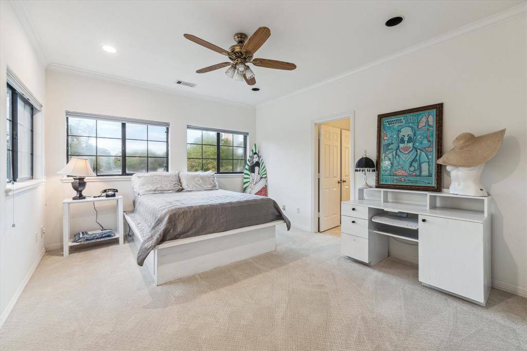 This is a spacious bedroom featuring ample natural light from large windows, a ceiling fan, and a neutral color palette. There is a large walk-in closet and it connects to a Jack & Jill bath.