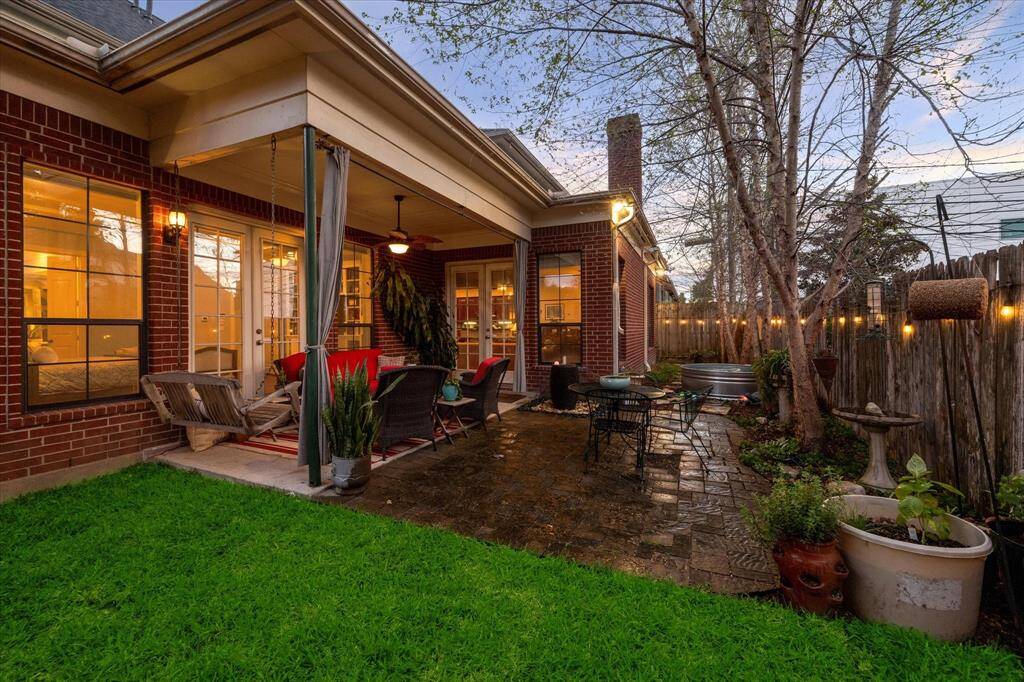 Charming backyard with a covered patio area, lush green trees and is perfect for evening relaxation.