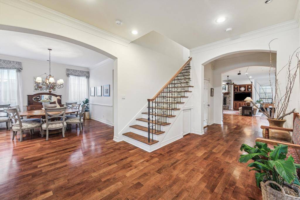 Elegant interior featuring hardwood floors, a graceful staircase, arched doorways, and a formal dining area, seamlessly transitioning to a lovely living space.