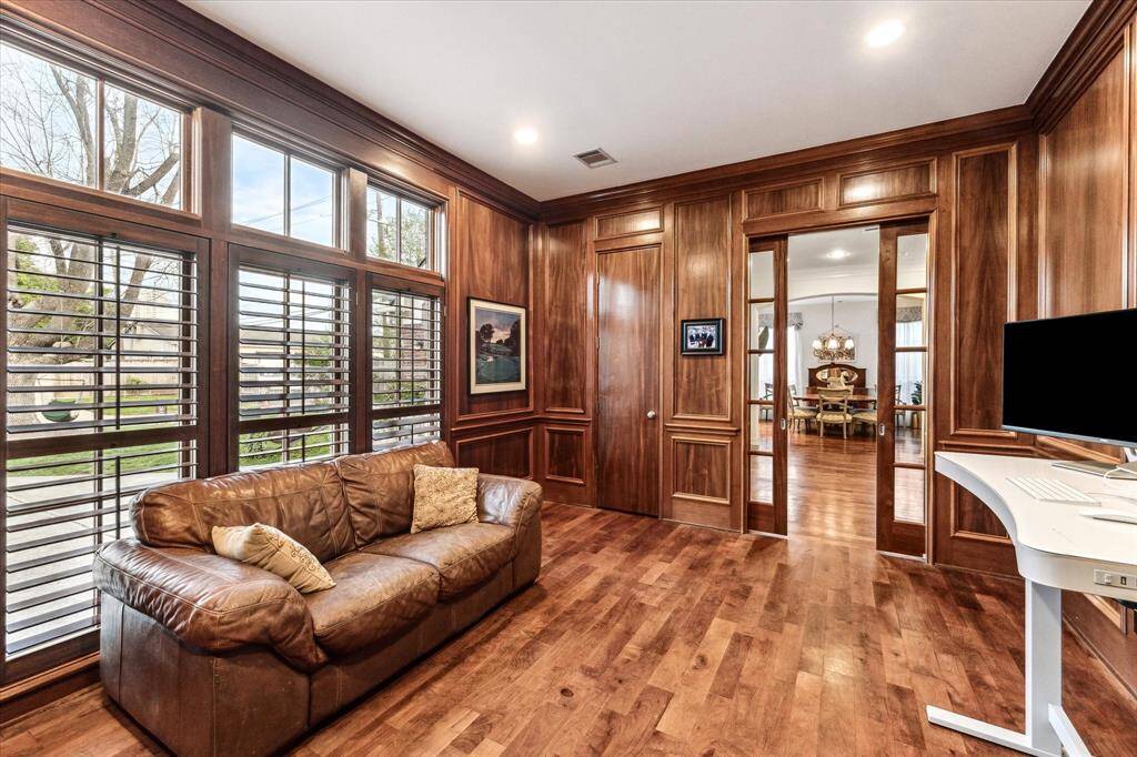 Home office with rich mahogany built-in bookshelves and cabinetry, complemented by warm-toned mesquite hardwoods. French doors lead into the space, suggesting a quiet, comfortable environment ideal for work or study.