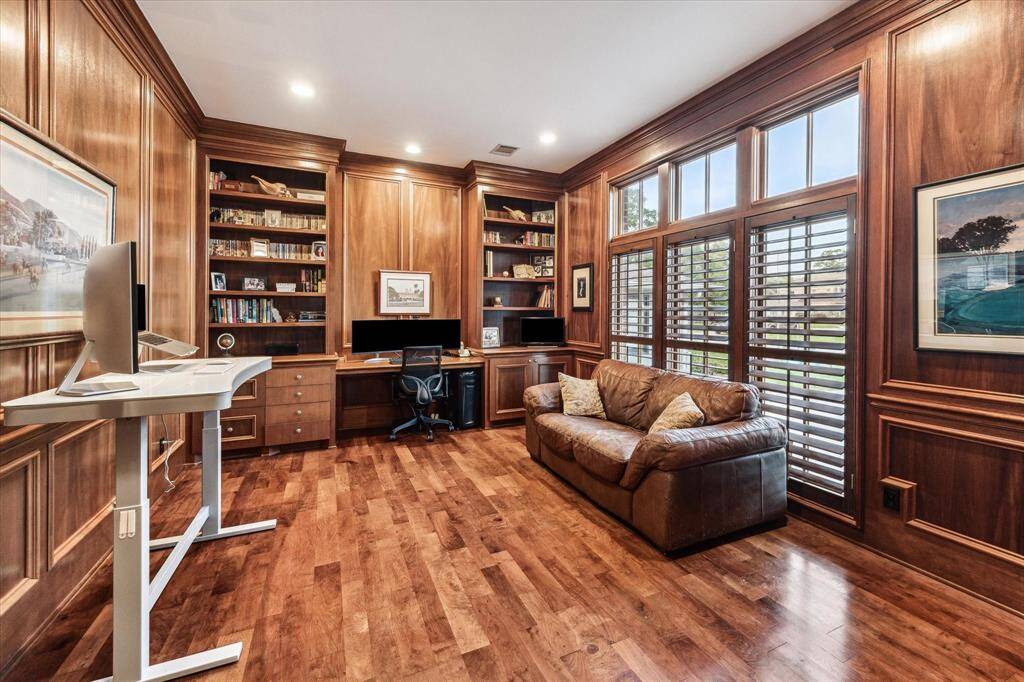 This is a spacious home office has ample natural light from large windows with plantation shutters.