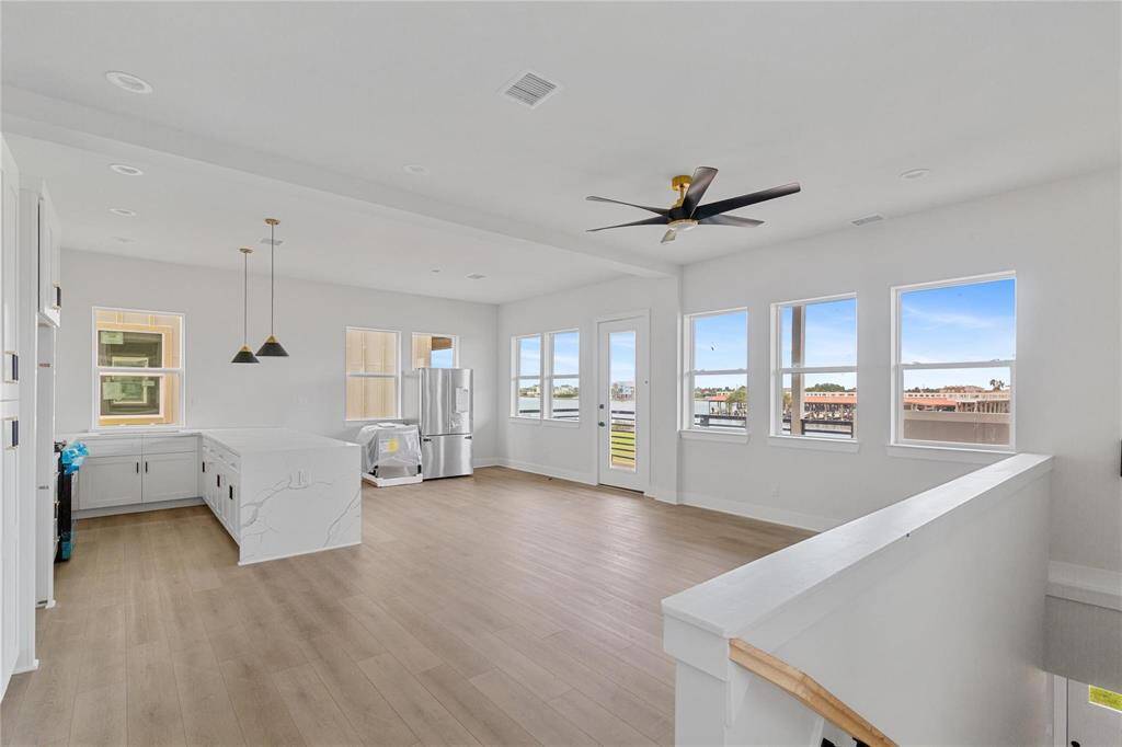 Bright, open-concept living space with contemporary finishes, including a sleek kitchen with stainless steel appliances, ample natural light from large windows, and a clear view of the bay.