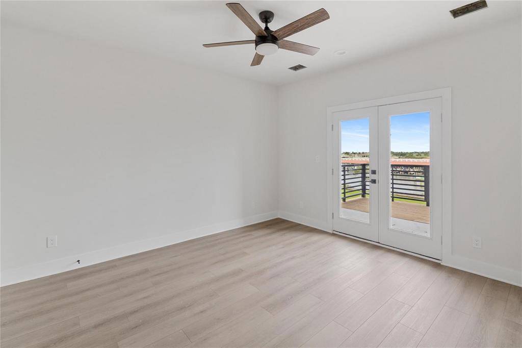 Primary bedroom on second floor featuring a ceiling fan and double doors to a deck with a bay view for relaxing morning and evenings