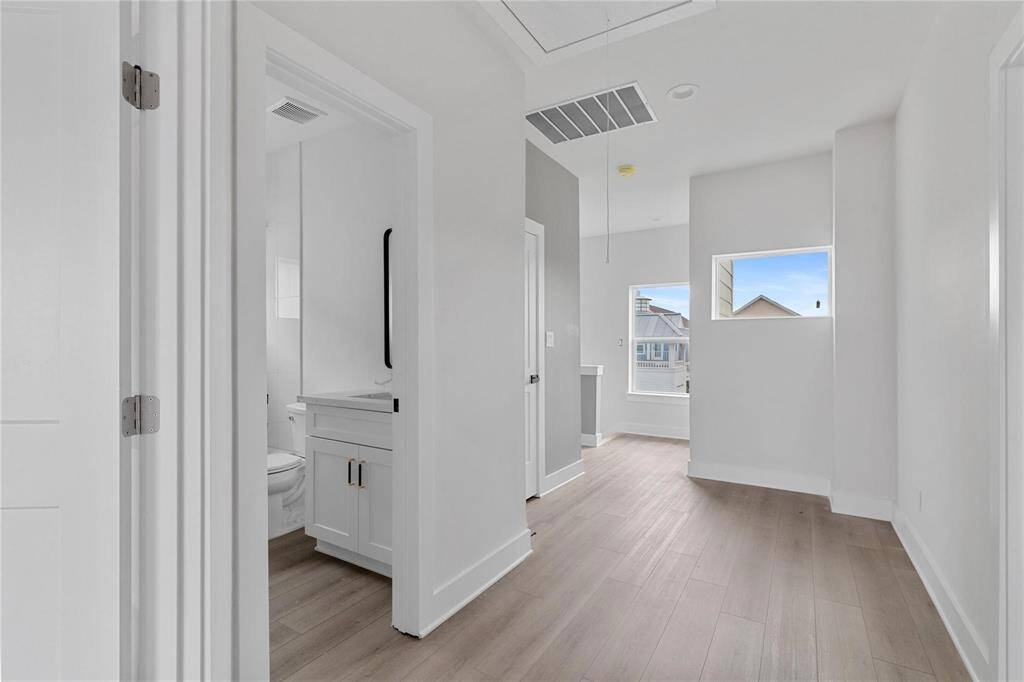 Bright hallway on the second floor with two bedrooms, two full bathrooms, balcony decks, and natural sunlight throughout
