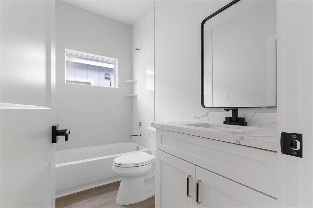 Representative Photo of Secondary bathroom with sleek hardware, quartz countertop, and beautifully tiled wall with at the end.