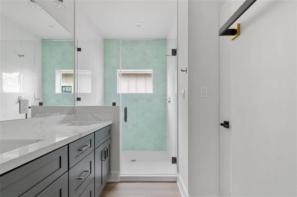 Representative Photo of Primary bathroom featuring a spacious shower with a stunning tiled accent wall, double sink vanity, and quartz countertops.