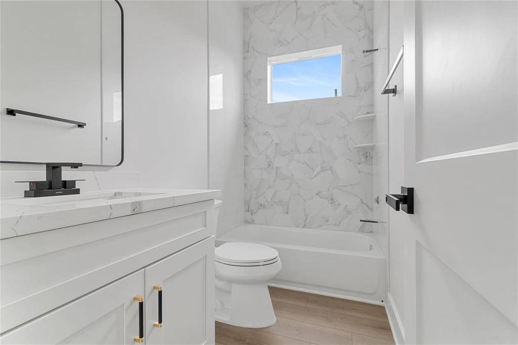 epresentative Photo of Secondary bathroom with sleek hardware, quartz countertop, and beautifully tiled wall with at the end.