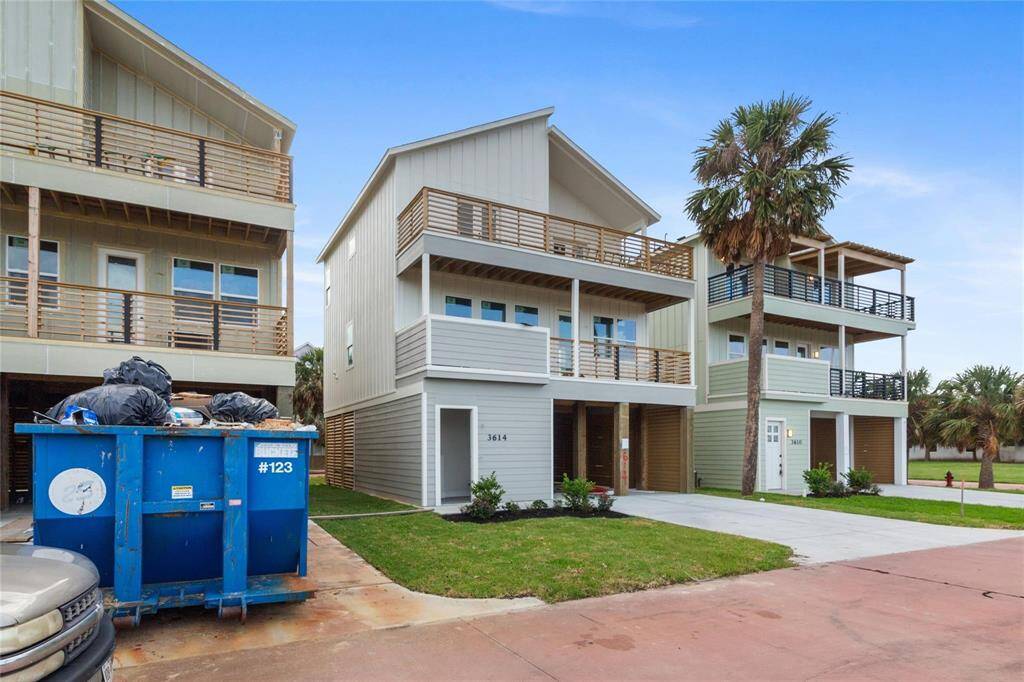 Multi-story home featuring a gray exterior with black trim and balconies, offering a spacious car ports and a fresh coastal vibe