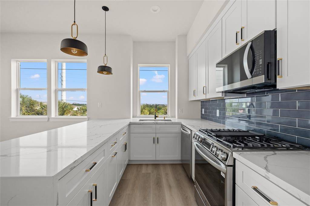 Full kitchen with stainless steel appliances including a refrigerator