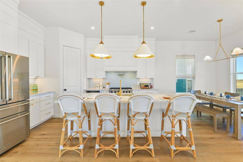 Elevate your gatherings with the spacious marble countertop island, featuring ample bar seating and sleek modern fixtures—perfect for hosting dinners of any size in style.