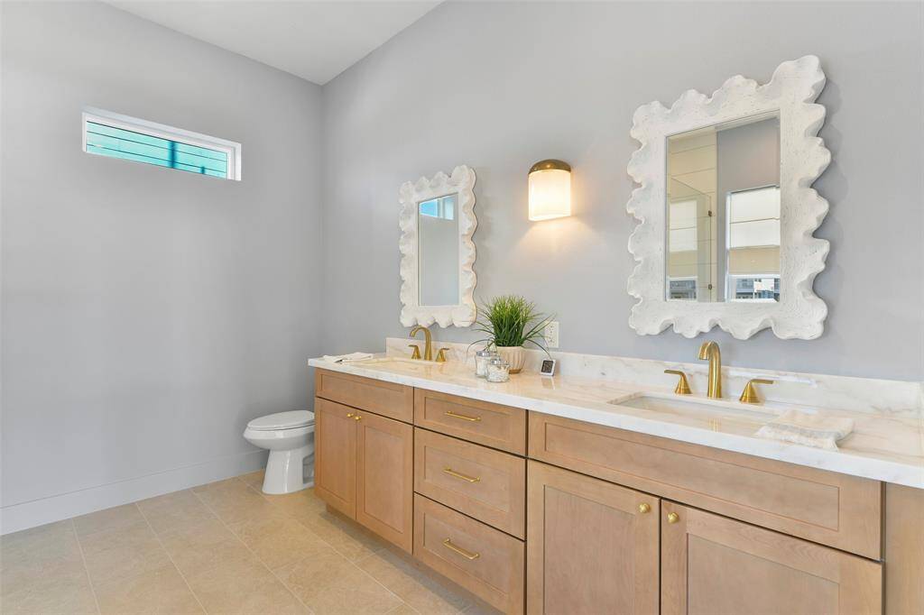 This elegant vanity combines ample counter space and custom-built cabinetry, all complemented by the timeless touch of brushed-gold hardware.