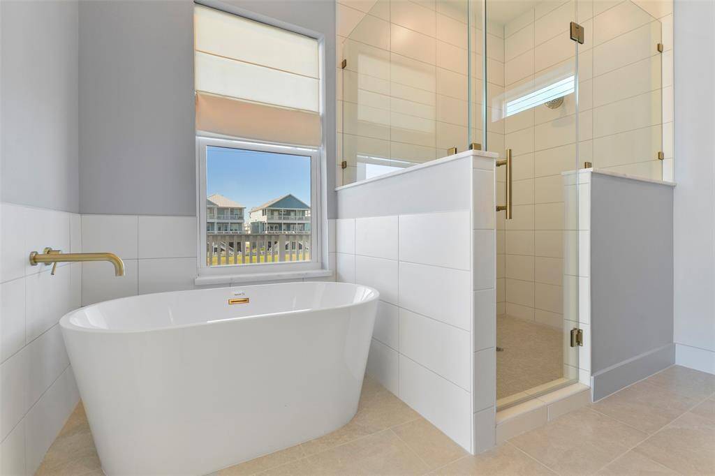 Indulge in luxury with a freestanding soaking tub and a custom-designed, oversized shower, both enhanced with elegant brushed-gold fixtures.