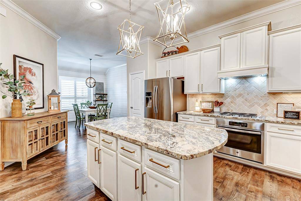 The kitchen island provides additional cabinetry for extra storage, while elegant pendant lights hang overhead, adding a touch of sophistication. Other highlights include a gas cooktop with a seamlessly integrated hood that blends beautifully with the cabinetry.