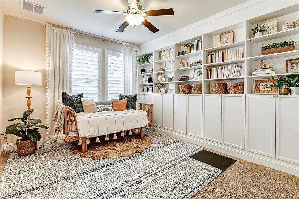 Guests will adore this bedroom, conveniently located at the front of the home. It features plush carpeting, a ceiling fan, and custom built-ins, added in 2022, providing both style and functionality.