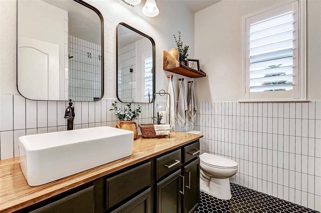 Every corner of this full bathroom reflects thoughtful design! Updates include stylish tile on the walls, a modern countertop with a vessel sink, stunning floor tiles, and two elegant framed mirrors.