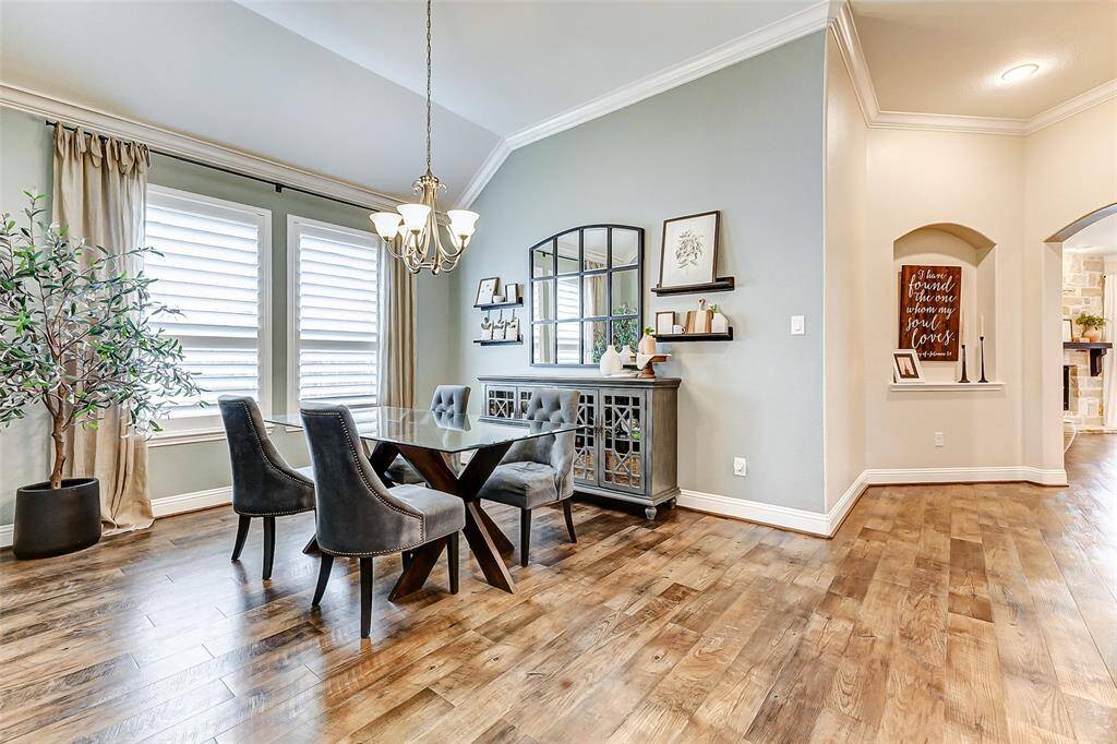Continuing past the entryway, you'll discover your elegant formal dining room, showcasing crown molding, plantation shutters, and designer paint. A stunning light fixture hangs overhead, adding the perfect finishing touch.