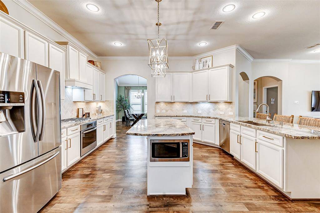 Welcome to your chef-inspired kitchen, where elegance meets functionality! Featuring stunning cabinetry with gold hardware, granite countertops paired with a stylish backsplash, ample lighting, and a spacious island with a breakfast bar, this kitchen is designed to impress.