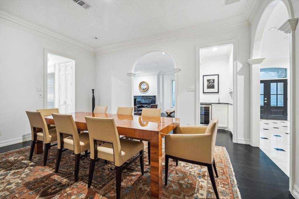 DINING ROOM - Bathed in natural light from large windows, this refined dining room offers a warm and inviting ambiance. Architectural details like crown molding and cased openings enhance its timeless appeal, making it the perfect setting for memorable gatherings.