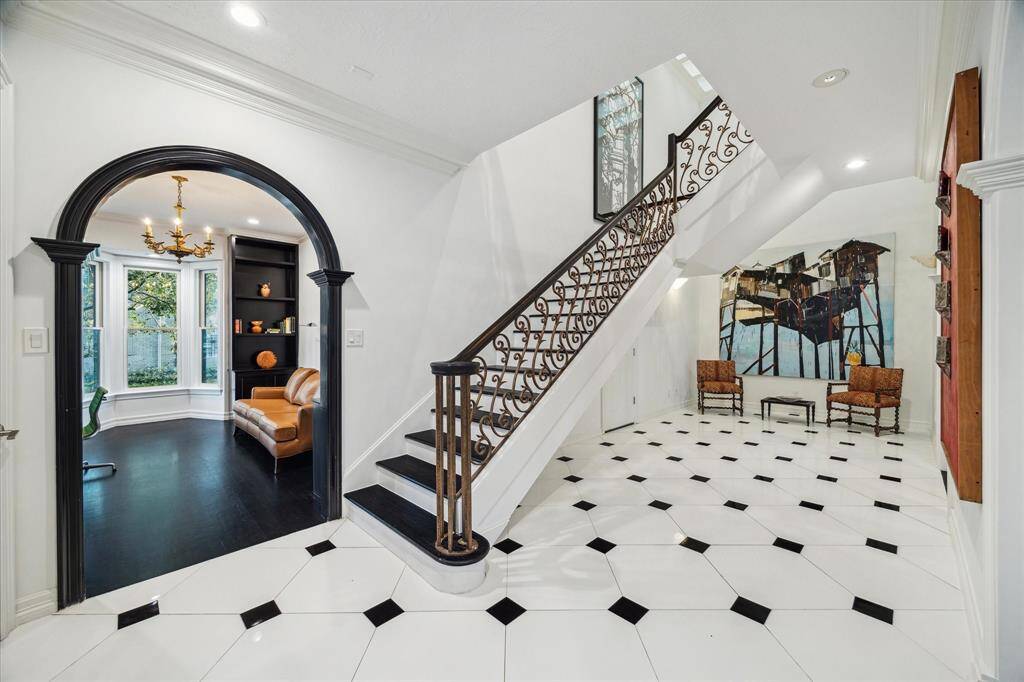 FOYER - A sophisticated entryway leads to the richly appointed study, featuring custom-built shelving and a picturesque bay window. Black-and-white diamond-pattern tile flooring enhances the home’s classic yet modern aesthetic.