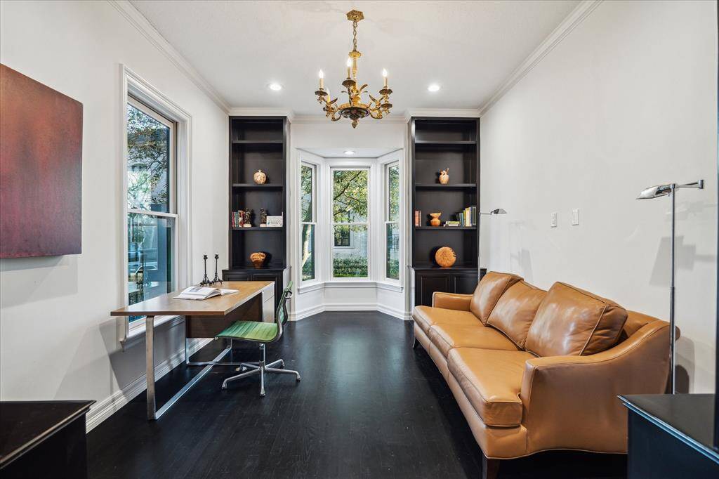 STUDY - This distinguished study is a haven for relaxation and productivity, featuring rich ebonized hardwood flooring and built-in shelving with custom wine racks. Large windows invite abundant natural light while offering serene front-yard views.