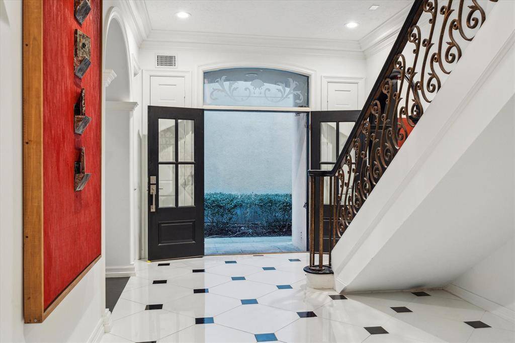 FOYER - The foyer’s custom French doors, crowned with John Meek Design Studio glass, bathe the space in natural light. Dual coat closets flank the entrance, offering both function and symmetry.