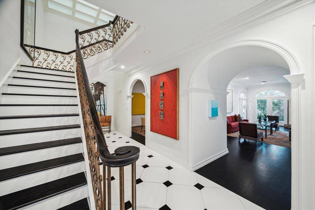 FOYER - The grand foyer welcomes guests with soaring 10-foot ceilings and a striking staircase with custom iron balusters. Thoughtfully designed cased openings create a seamless connection between the living spaces.