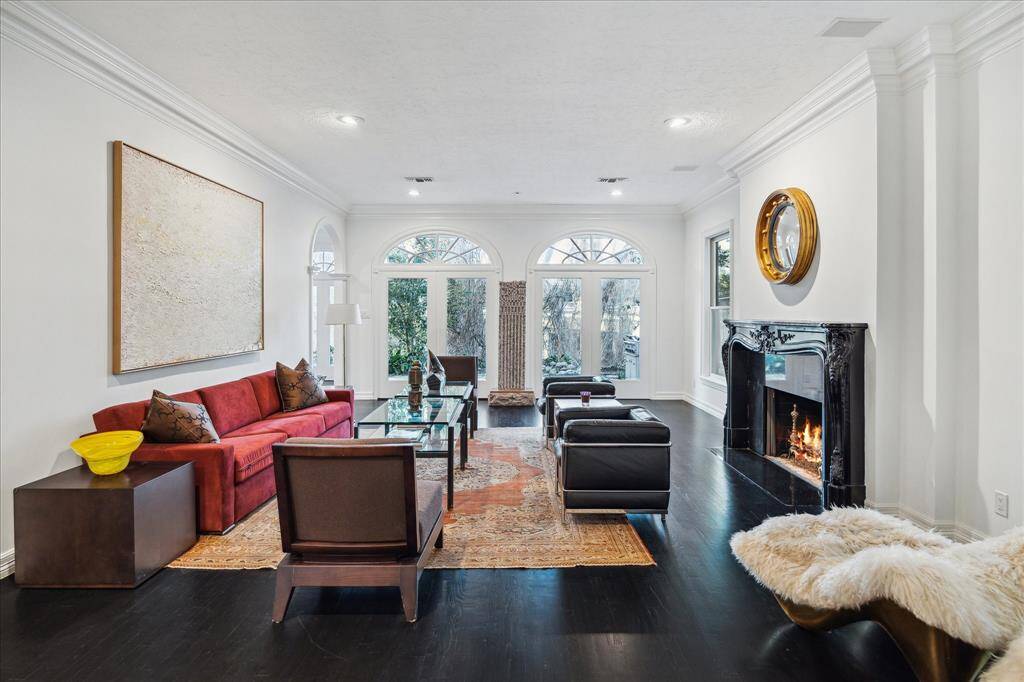 LIVING ROOM - Oversized arched windows frame scenic backyard views, allowing natural light to illuminate the inviting living space. A gaslog fireplace with a black granite hearth adds warmth and sophistication.