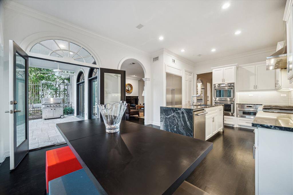 BREAKFAST ROOM - Open to the kitchen, this breakfast area serves as the perfect extension of the home’s heart. In-ceiling speakers, crown molding, and warm hardwood flooring enhance its inviting appeal.