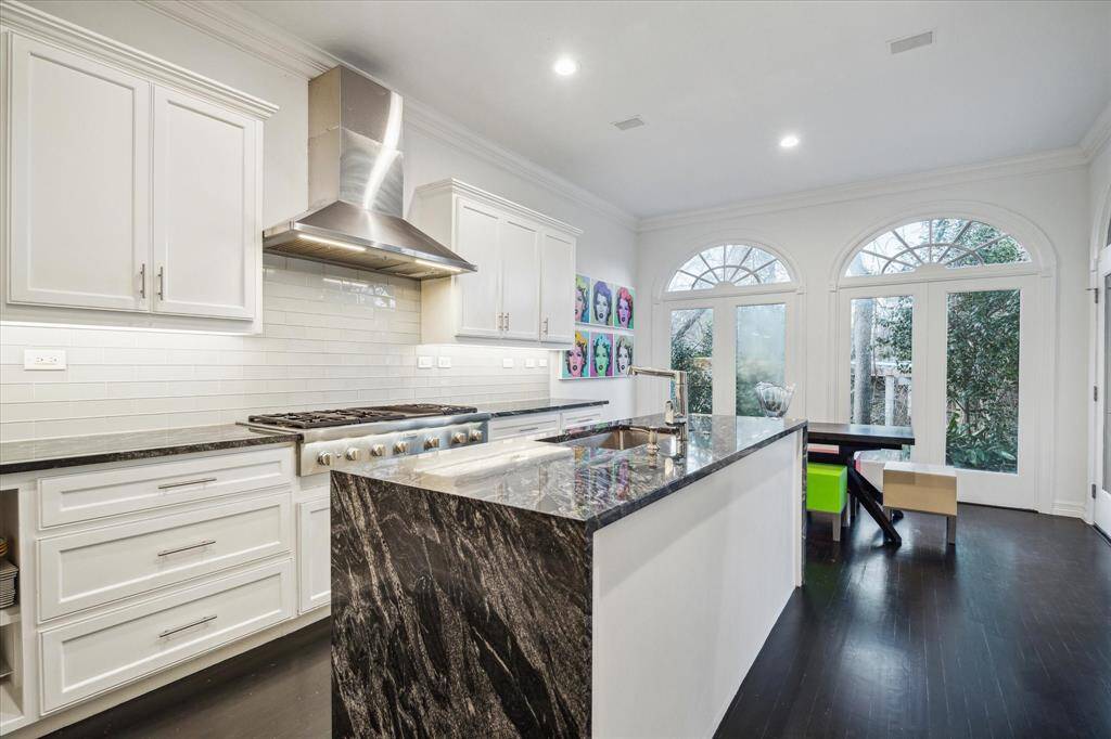 KITCHEN - Designed for both form and function, the chef’s kitchen boasts a large island with waterfall quartz countertops and top-of-the-line Thermador appliances. A six-burner gas cooktop with a griddle, dual wall ovens, and a spacious pantry make this a dream for culinary enthusiasts.