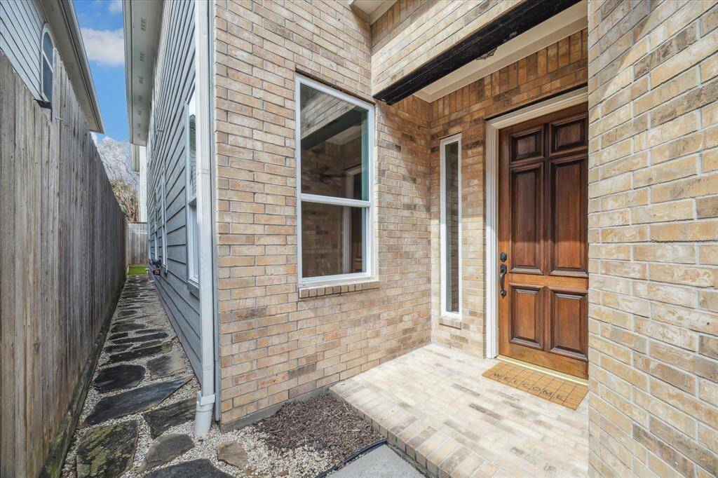 The secure entryway for guests boasts a handsome door complemented by attractive molding and classic brickwork, offering a warm and inviting first impression. This entrance also provides convenient access to the charming rear patio, ideal for relaxation and entertaining.