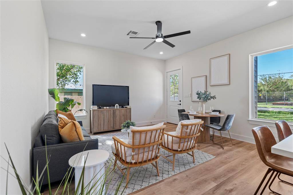 The living room is bathed in natural light, thanks to large windows that surround the space. A bright and welcoming area, perfect for relaxation and gatherings.