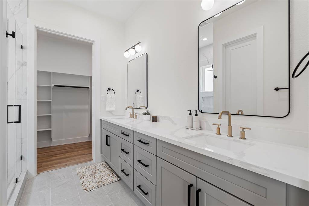 The ensuite features double sinks with gold faucets and sleek gray cabinets, creating a stylish contrast that's both modern and elegant