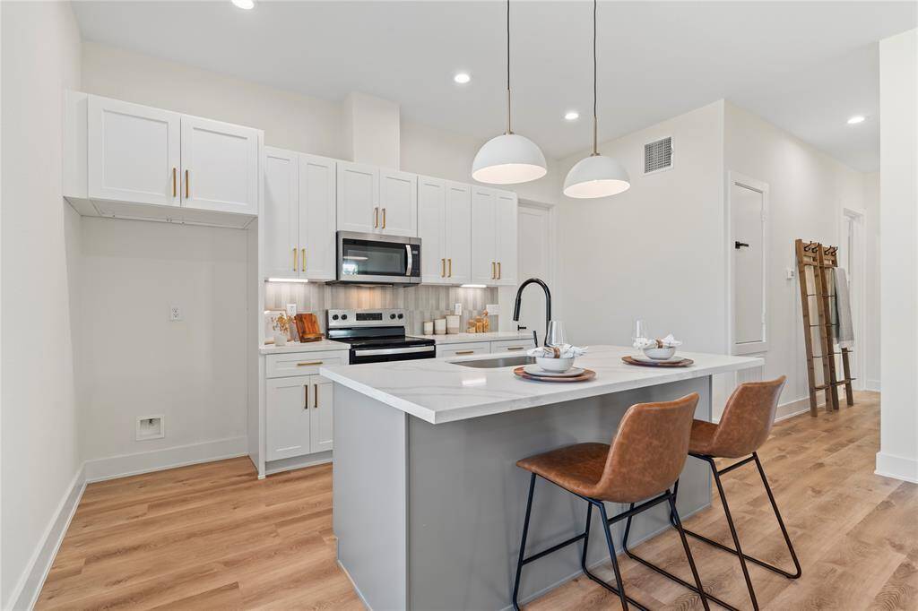 White cabinets, gold hardware, and a light backsplash combine to create a bright, airy feel with a touch of modern elegance in the kitchen