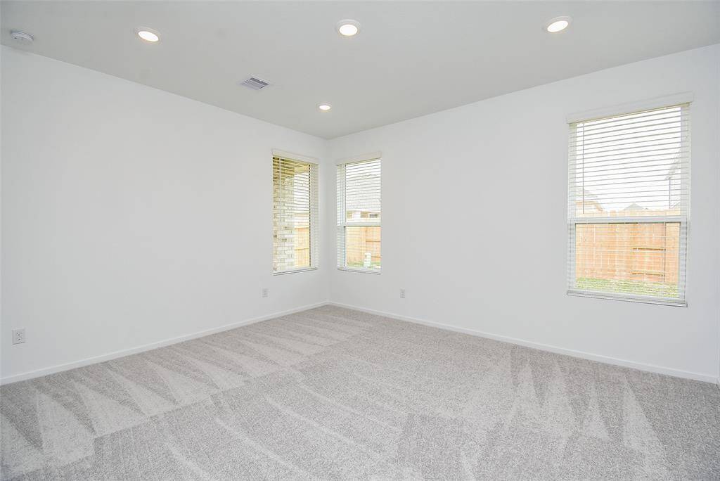 View of the primary bedroom which looks out on to the backyard.  New, neutral carpet will fit with your decor. (staged)