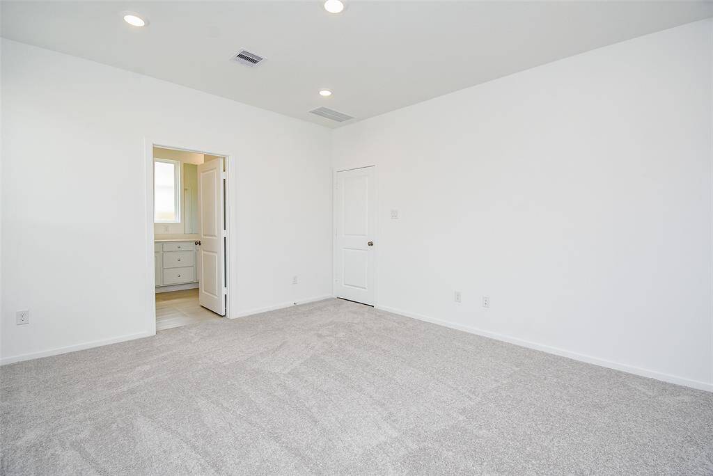 View of the primary bedroom shows the door into the room and the door into the bathroom.  This large room has lots of wall space for your furniture.
