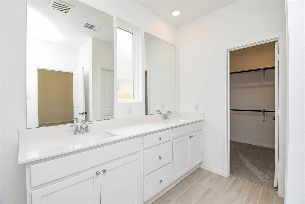 Primary bath with dual sinks and mirrors.  High quartz countertops and undermount sinks.