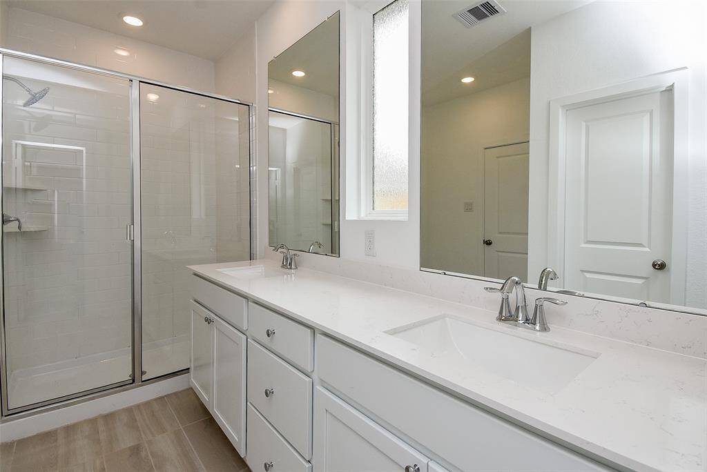 Huge, tiled shower with glass doors for a clean, modern look.