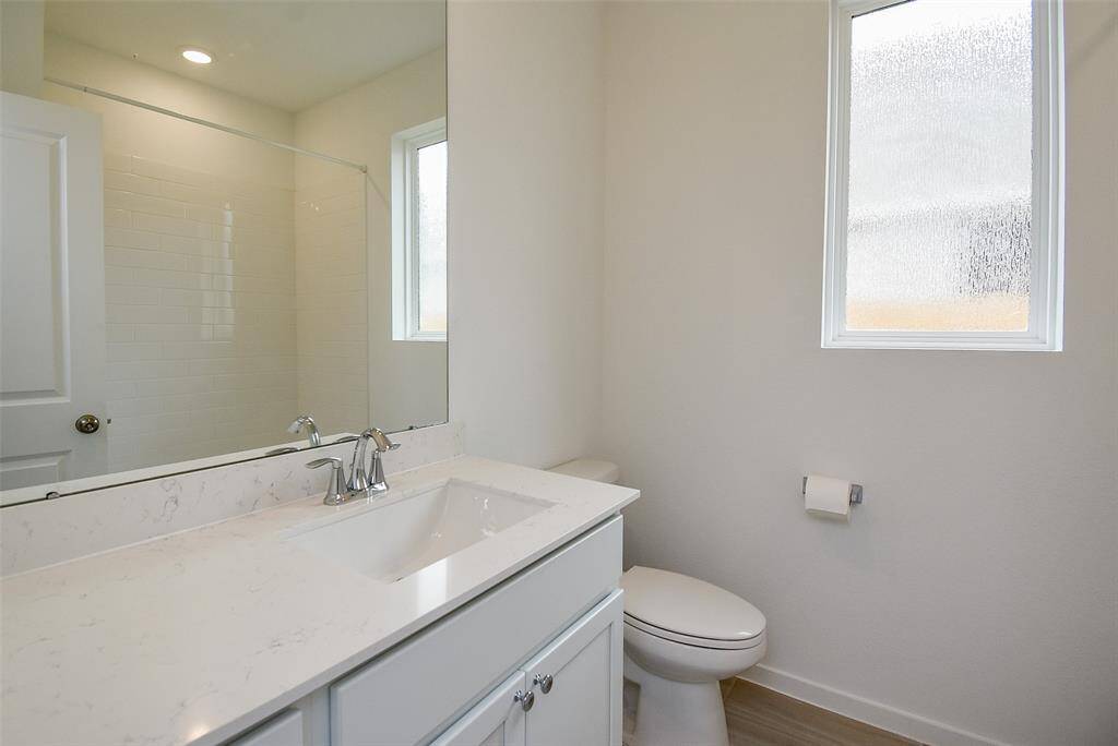 Secondary bath has generous quartz counter space and cabinets below.