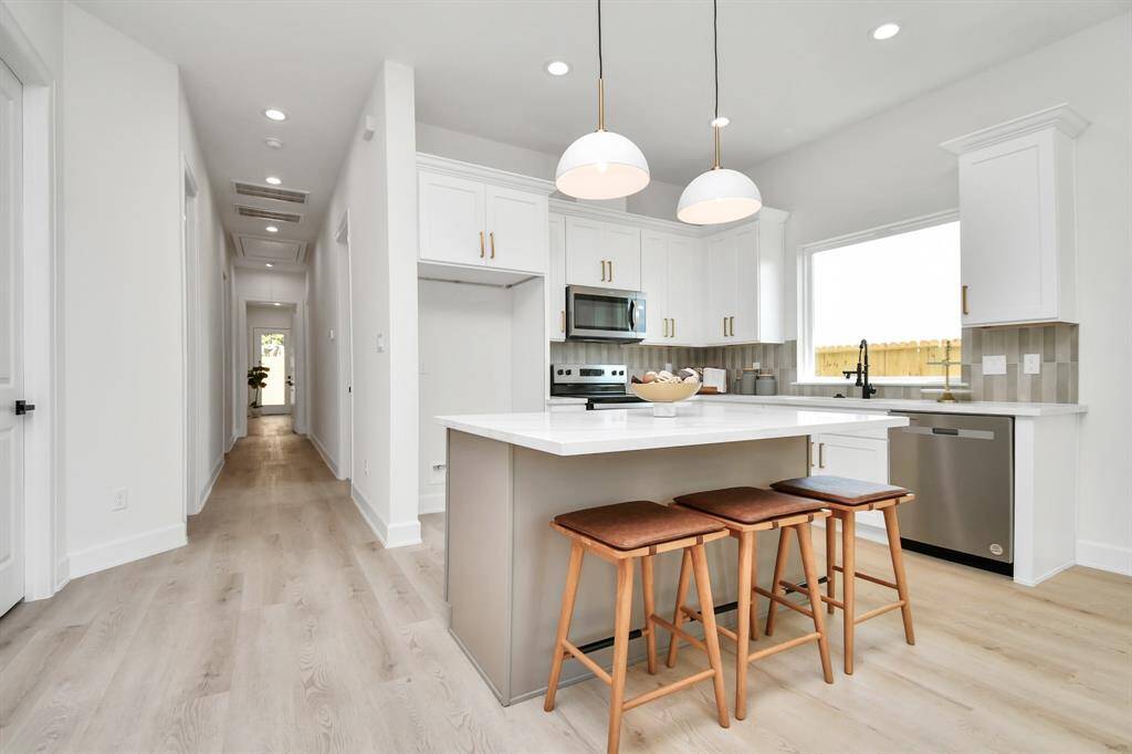 The kitchen highlights a charming farmhouse sink set beneath an expansive window, allowing natural light to flood the space and create a warm, inviting atmosphere. This setup not only adds a touch of rustic elegance but also offers a serene view while you work in the kitchen.