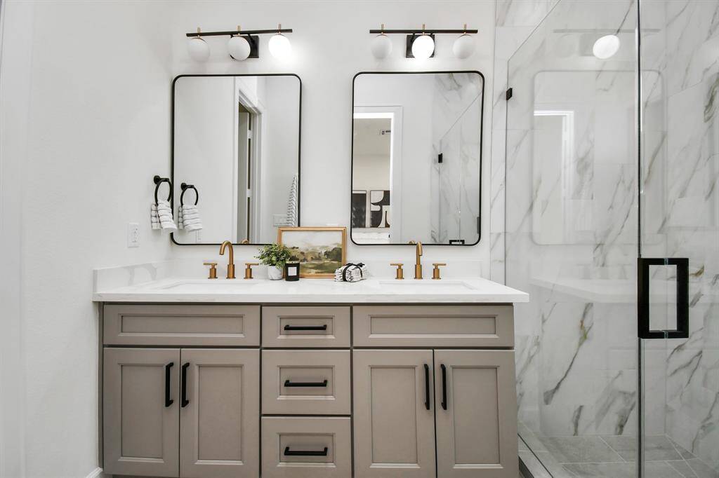 The primary bathroom showcases dual sinks with an expansive countertop, providing ample space for daily essentials and creating a luxurious, functional setup. The generous counter area enhances convenience and adds a touch of elegance to the space.
