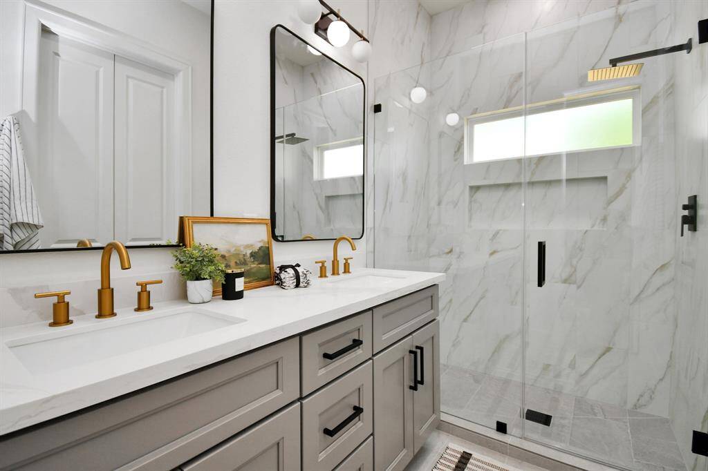 The primary bath exudes sophistication with its crisp white cabinetry and floor-to-ceiling tiles in the spacious, luxurious shower, which includes a grand niche for added convenience and style.