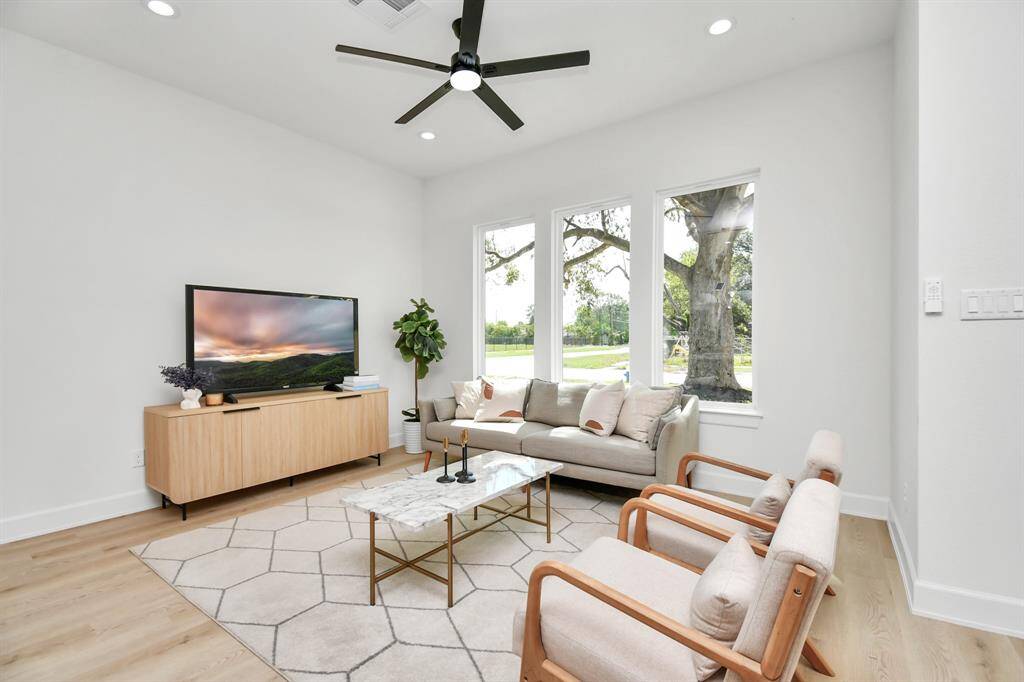 The living room is filled with abundant natural light, streaming through large windows that brighten the entire space.