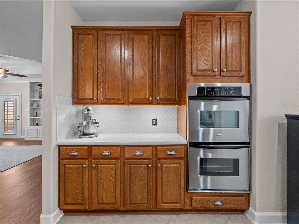 Functional kitchen layout with quartz countertops, tile backsplash, and stainless steel double ovens.