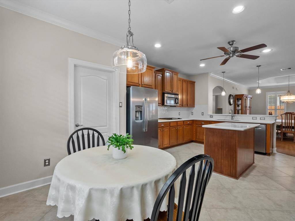 Open kitchen and breakfast nook with tile flooring, quartz countertops, and stainless steel appliances.